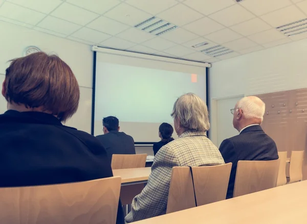 Publiek op proefschrift presentatie in een klaslokaal. — Stockfoto