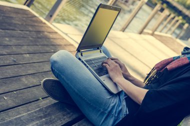 Nehir, bir parkta dizüstü bilgisayar kullanan genç kadın.