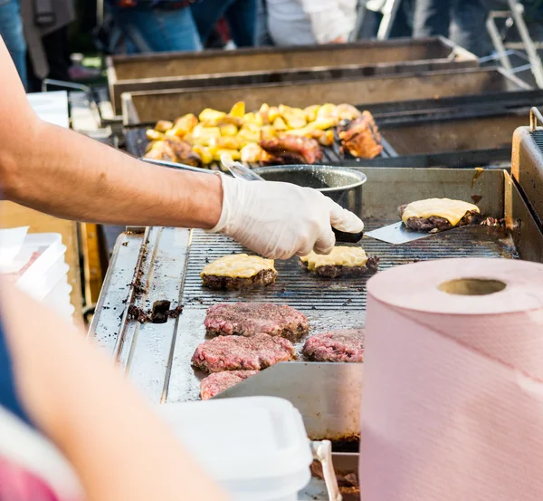 Chef preparare gustosi hamburger allo stand all'aperto . — Foto Stock