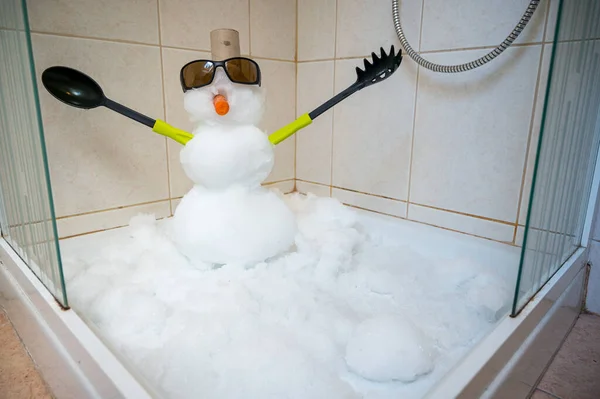 Malý sněhulák postavený uvnitř sprchy s příbory pro ruce. — Stock fotografie
