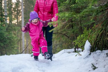Anne ve kızı karlı bir ormanda yürüyor..
