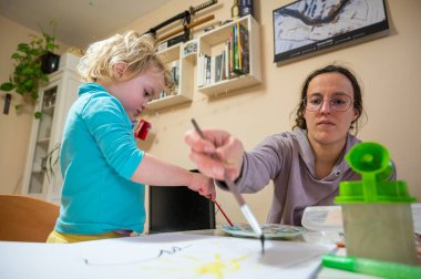 Annesiyle resim yapan ve resim çizen tatlı bir kız..