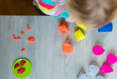 Evde renkli hamurla oynayan çocuğun ayrıntıları.