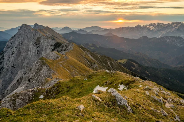 Spektakulärer Blick auf die Berge: Sonne steigt über hohen Grat in der Ferne. — Stockfoto