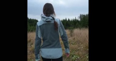 Genç bir kadın çam ormanlarında yürüyor..