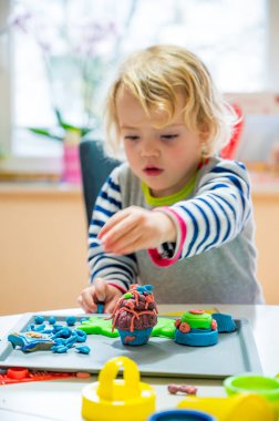 Bir sürü renkli çörekle oynayan tatlı bir kız..