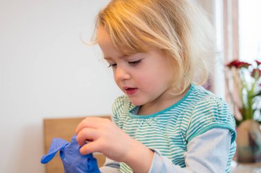 Evde plastik eldivenlerle oynayan tatlı sarışın kız..