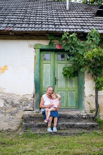 Grandmother sitting with her grandmother in front of her old house. — Stock Photo, Image