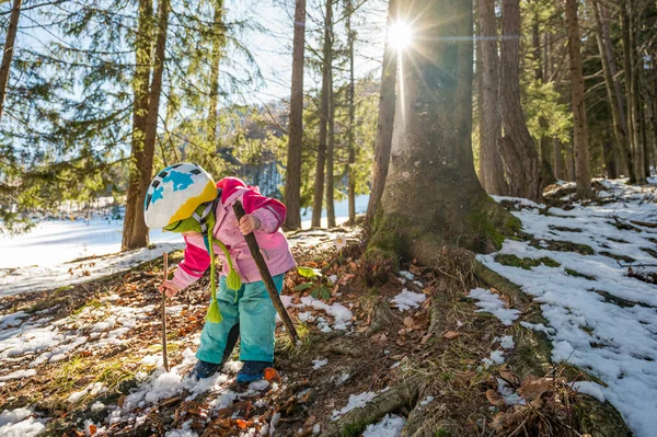 Söt flicka bär hjälm promenader genom vinterskogen. — Stockfoto