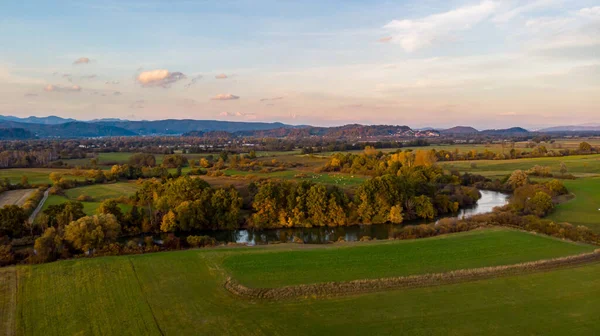 Spectacular aerial panorama of river flowing through fields at sunset. — Stock Photo, Image