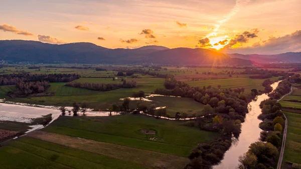 Spectacular aerial panorama of river flowing through fields at sunset. — Stock Photo, Image