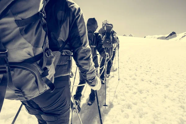 Corda ponto de vista membro da equipe com montanhistas andando sobre neve e gelo em tempo ensolarado. — Fotografia de Stock