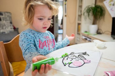 Evde cam renkler kullanarak balık çizen tatlı bir kız..