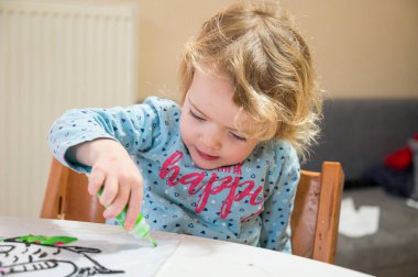 Evde cam renkler kullanarak balık çizen tatlı bir kız..