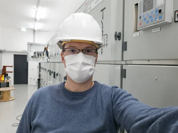 Ingeniero joven trabajando en subestación eléctrica con una máscara facial. — Foto de Stock