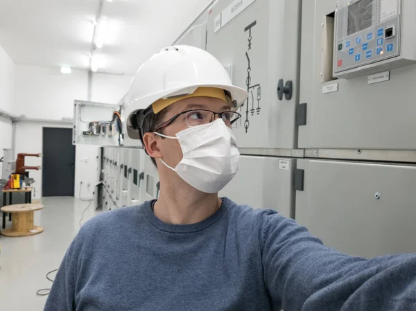 Ingeniero joven trabajando en subestación eléctrica con una máscara facial. — Foto de Stock