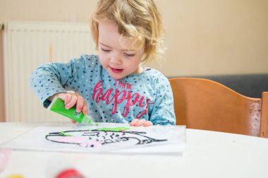 Evde cam renkler kullanarak balık çizen tatlı bir kız..