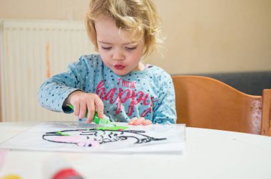 Evde cam renkler kullanarak balık çizen tatlı bir kız..