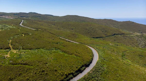 Aerial panorama of road crossing island ridge surrounded with lush vegetation. — ストック写真