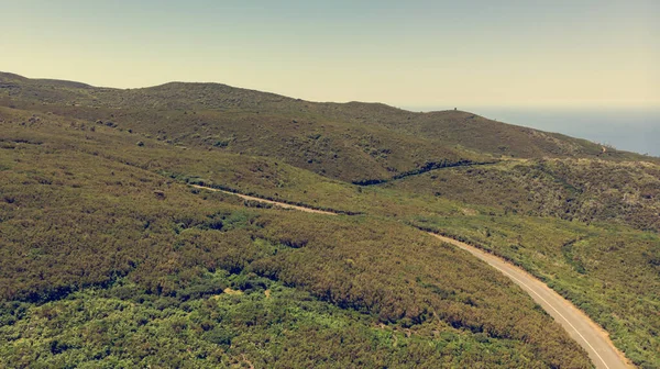 Aerial panorama of road crossing island ridge surrounded with lush vegetation. — ストック写真