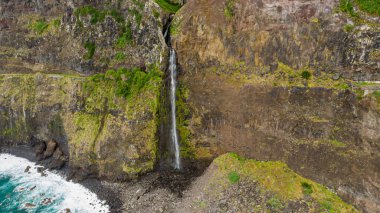 Volkanik kayalıklardan okyanusa düşen şelale.