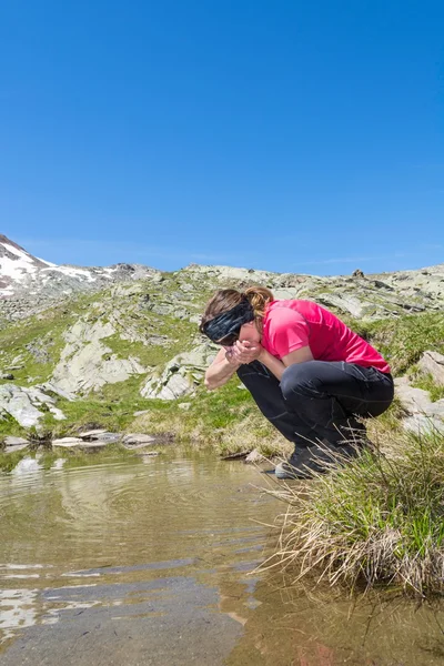 Chica joven bebiendo agua limpia del lago — Foto de Stock