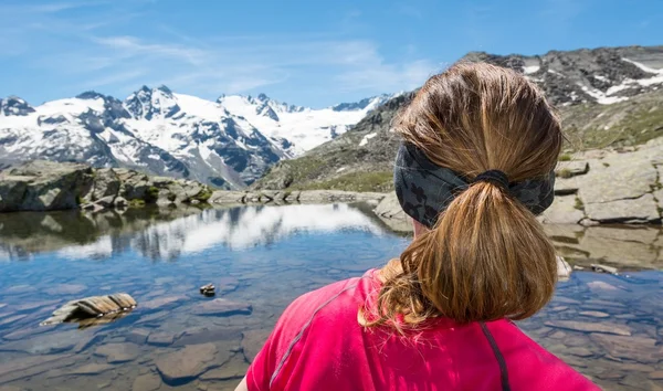 Mladá žena sleduje horské jezero — Stock fotografie