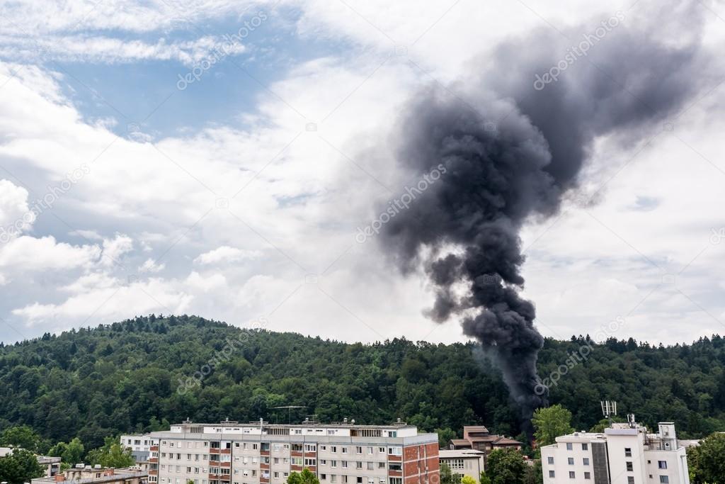 Column of black smoke rising above residential buildings.