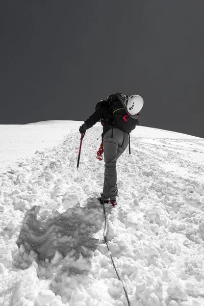 Mulher alpinista ascendendo uma encosta nevada . — Fotografia de Stock