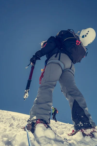 Vrouwelijke klimmer oplopende een besneeuwde helling. — Stockfoto