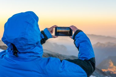 Kadın ona telefon ile dağ fotoğraf çekme.