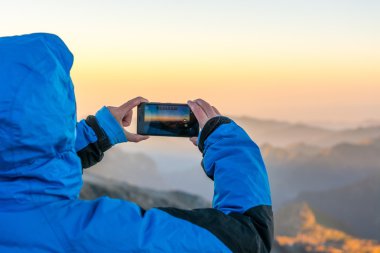 Kadın ona telefon ile dağ fotoğraf çekme.