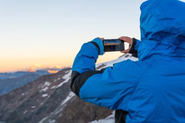 Kadın ona telefon ile dağ fotoğraf çekme.