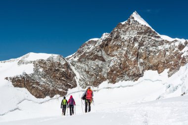 Grup bir buzulun üzerinde yürüyen dağcıların.