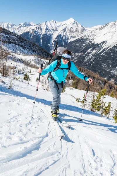 Ung kvinna stigande en lutning på skidor. — Stockfoto