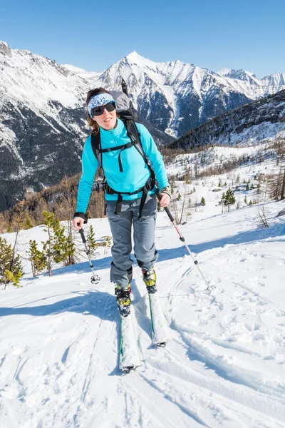 Ung kvinna stigande en lutning på skidor. — Stockfoto