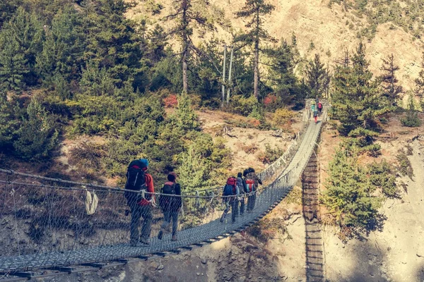 Trekkers che attraversano un ponte sospeso . — Foto Stock