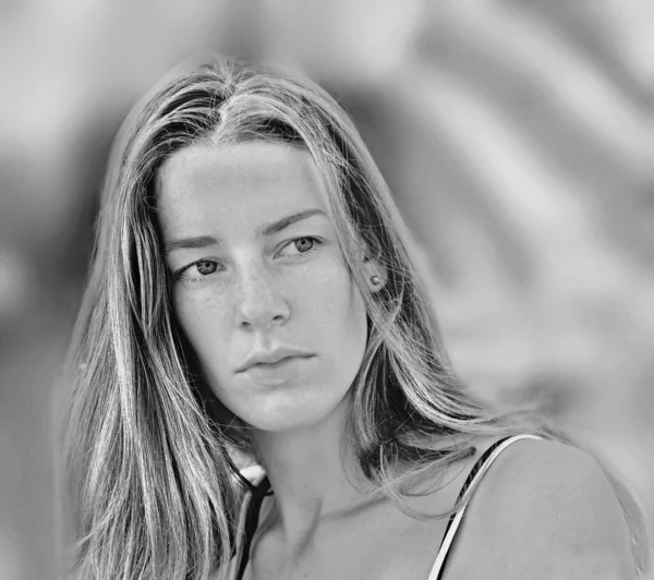 soft black and white frontal portrait of a very pretty young woman with long hair. and middle parting. She doesn\'t look at the camera. soft color gradations.