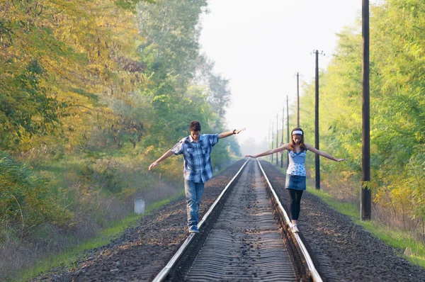 Adolescente menina e menino equilibrando em trilhos — Fotografia de Stock