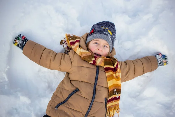 小男孩躺在雪地里 造出星形 儿童冬季活动 — 图库照片