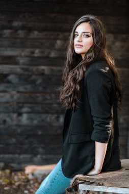 Siyah ceketli güzel esmer bir kızın yan görünümü.
