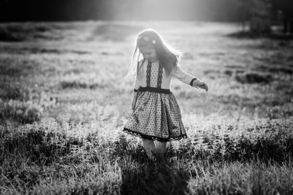 Outdoors black and white photo of little girl walking through the grass