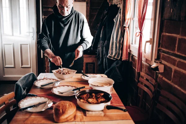 夕食は窓のそばのテーブルで出された サラダを作る老人 — ストック写真