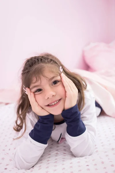 小さなブルネット女の子嘘をついています彼女のベッドでパジャマ — ストック写真