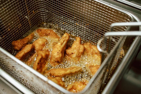 Kızarmış tavuk nuggetları kızartma makinesinde. Restoran yemeği hazırlığı.