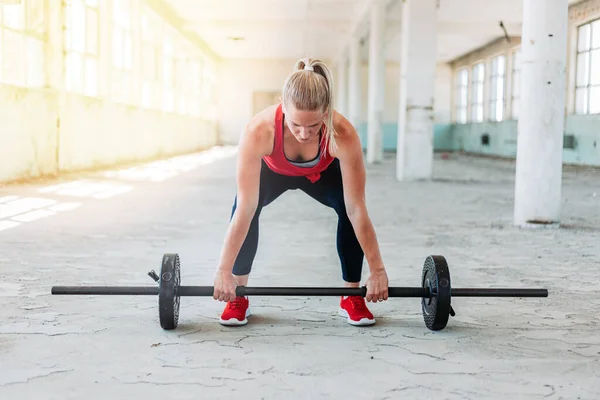 Fit blond woman weight lifting in red sportswear. Training, active lifestyle.