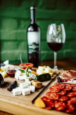 İtalyan aperatifleri yanında şarap şişesi ve bardakla ahşap tahtada..