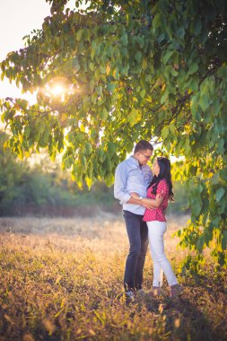 Genç çift ağacın altında sarılıyor. Romantizm, romantik jestler