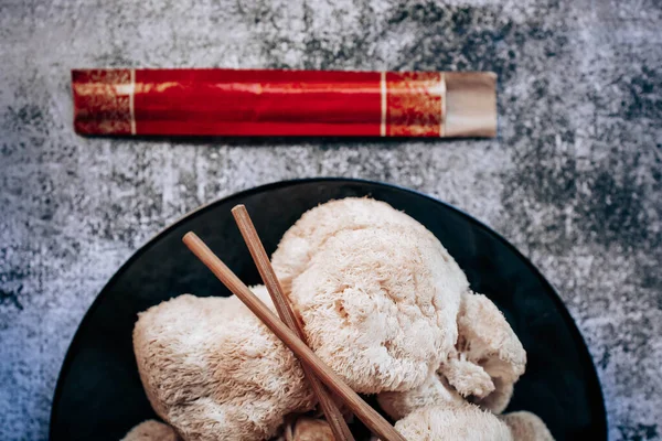 Hericium erinaceus 'un ya da Aslanların Çin çubuklarıyla kaplı bir tabakta mantar mantarlarının en üst görüntüsü. Tıbbi mantar konsepti