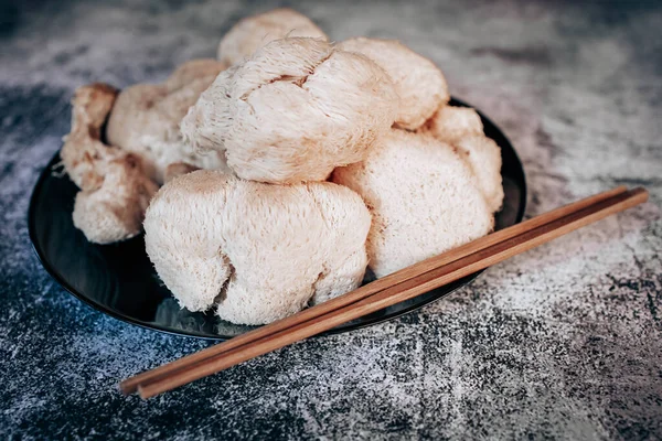 Hericium erinaceus or Lions mane mushrooms on a plate with Chinese sticks. Medical mushroom concept